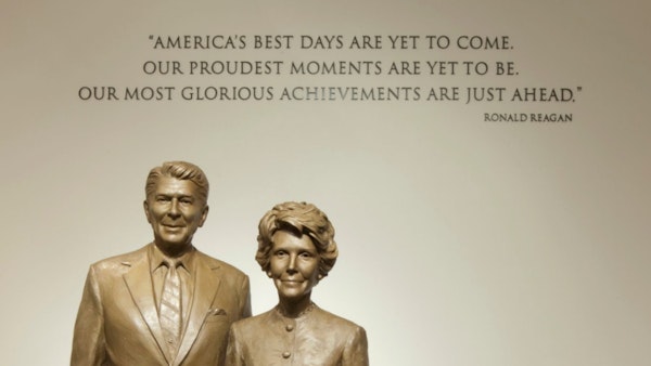 Nancy and Ronald Reagan Statues in front of a Reagan Quote