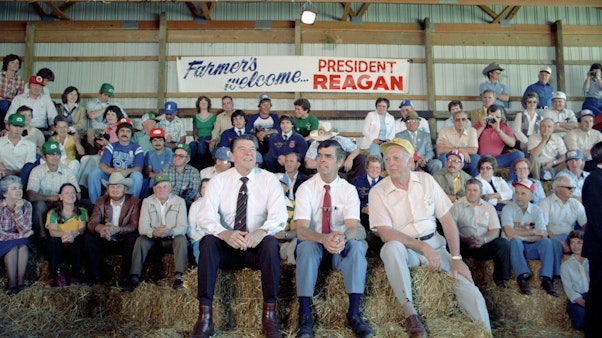 Farmers Welcome President Reagan Large crowd of men sitting on bales of hay in a barn