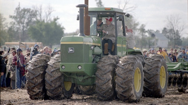 President Reagan rides a John Deer Tractor with a farmer Two men ride on a Green Tractor in ball caps