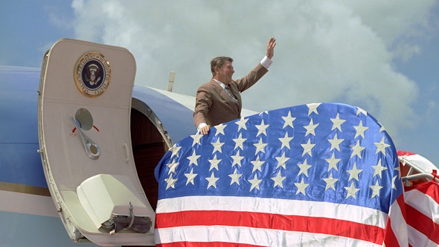 Reagan exiting the Air Force One with American flag draped over the ramp Ronald Reagan waves from plane with American flag